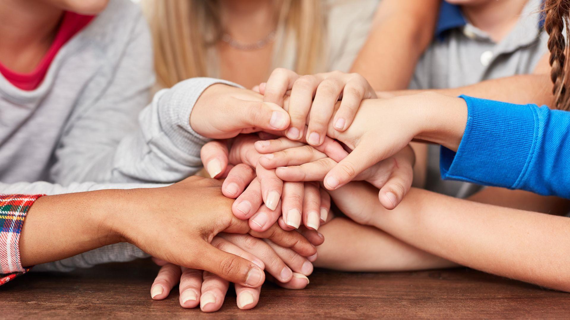 Kinder unterschiedlicher Herkunft legen gemeinsam ihre Hände zusammen